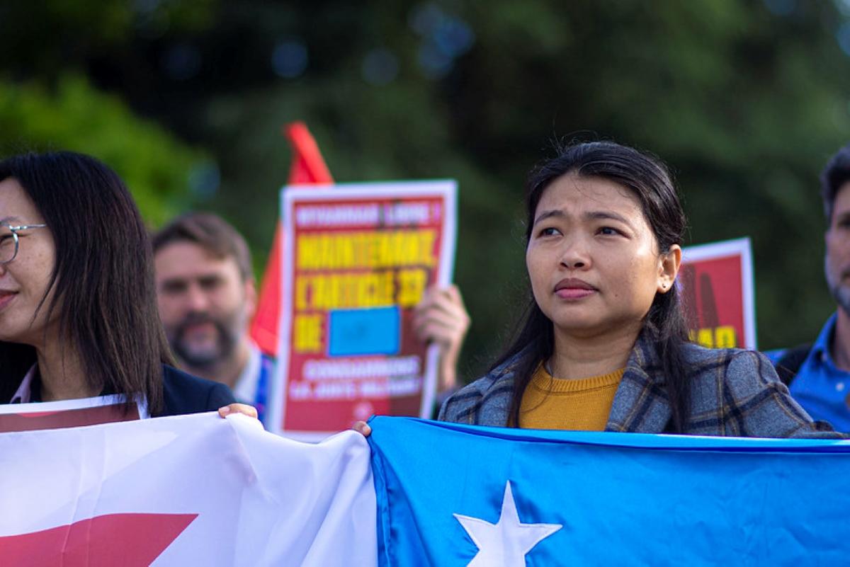 Khaing Zar Aung, Gewerkschafterin aus Myanmar, bei einer Demo in Genf mit einer Fahne.