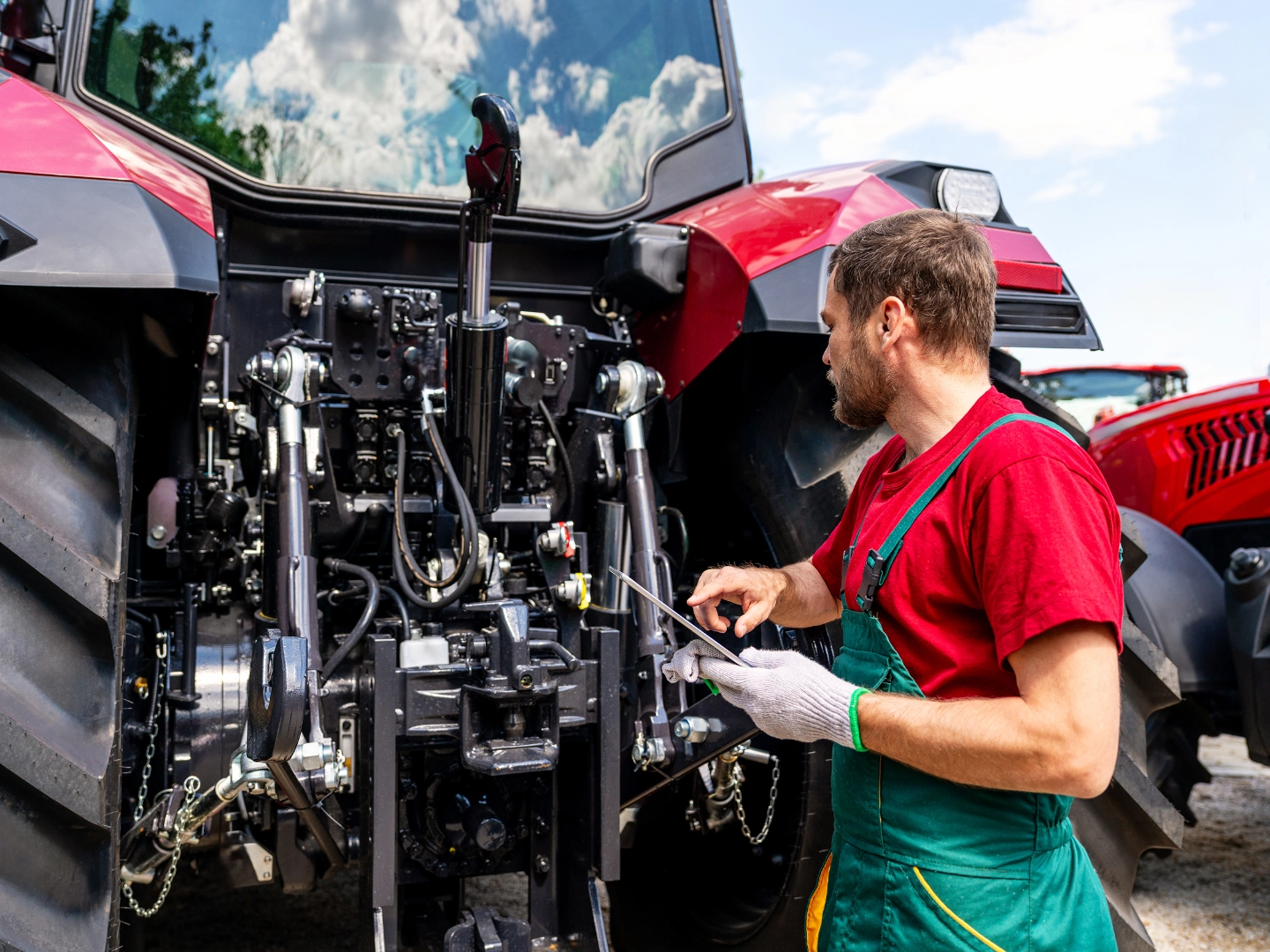 Ein männlicher Land- & Baumaschinenmechatroniker prüft einen Traktor mit einem Tablet