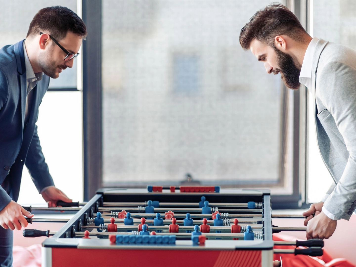 Zwei Kollegen spielen im Büro an einem Tischkicker