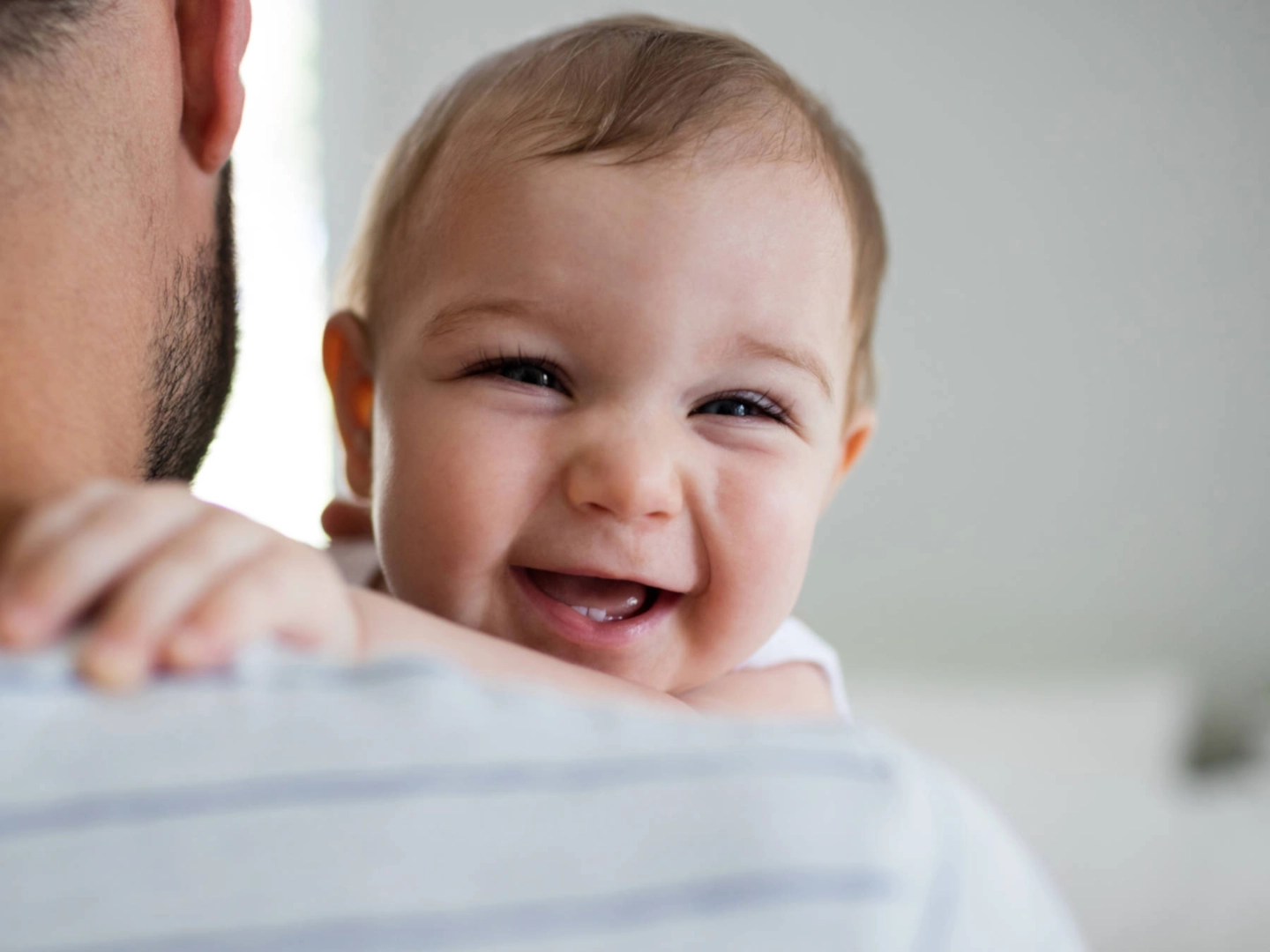 Ein lächelndes Baby auf dem Arm seines Vaters.
