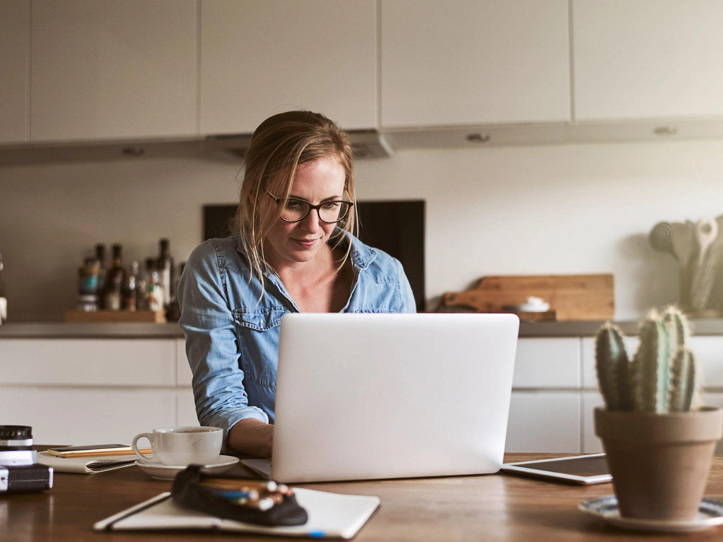 Junge Frau arbeitet in ihrer Küche mit einem Laptop