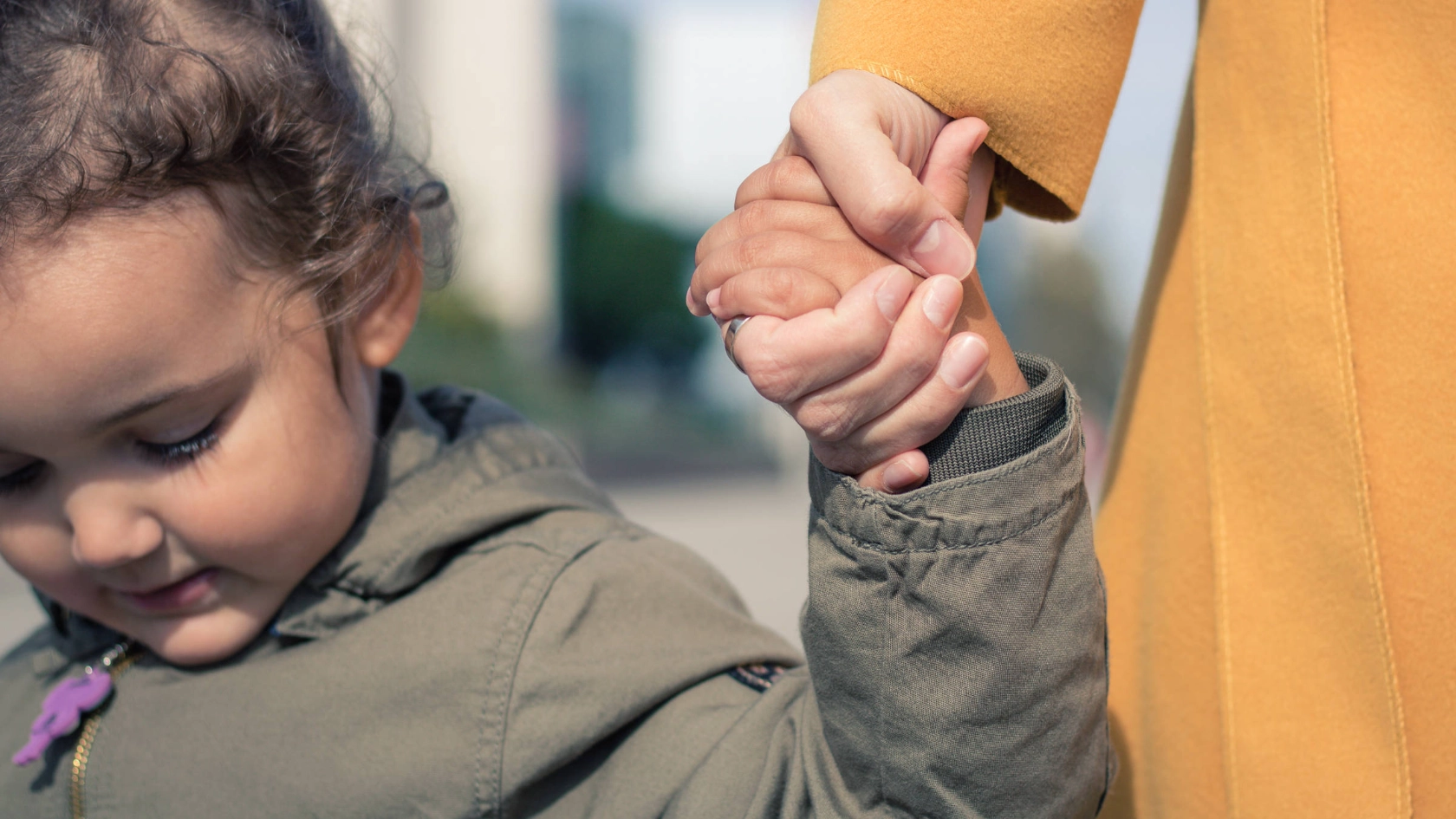 Ein kleines Mädchen hält die Hand eines Erwachsenen.
