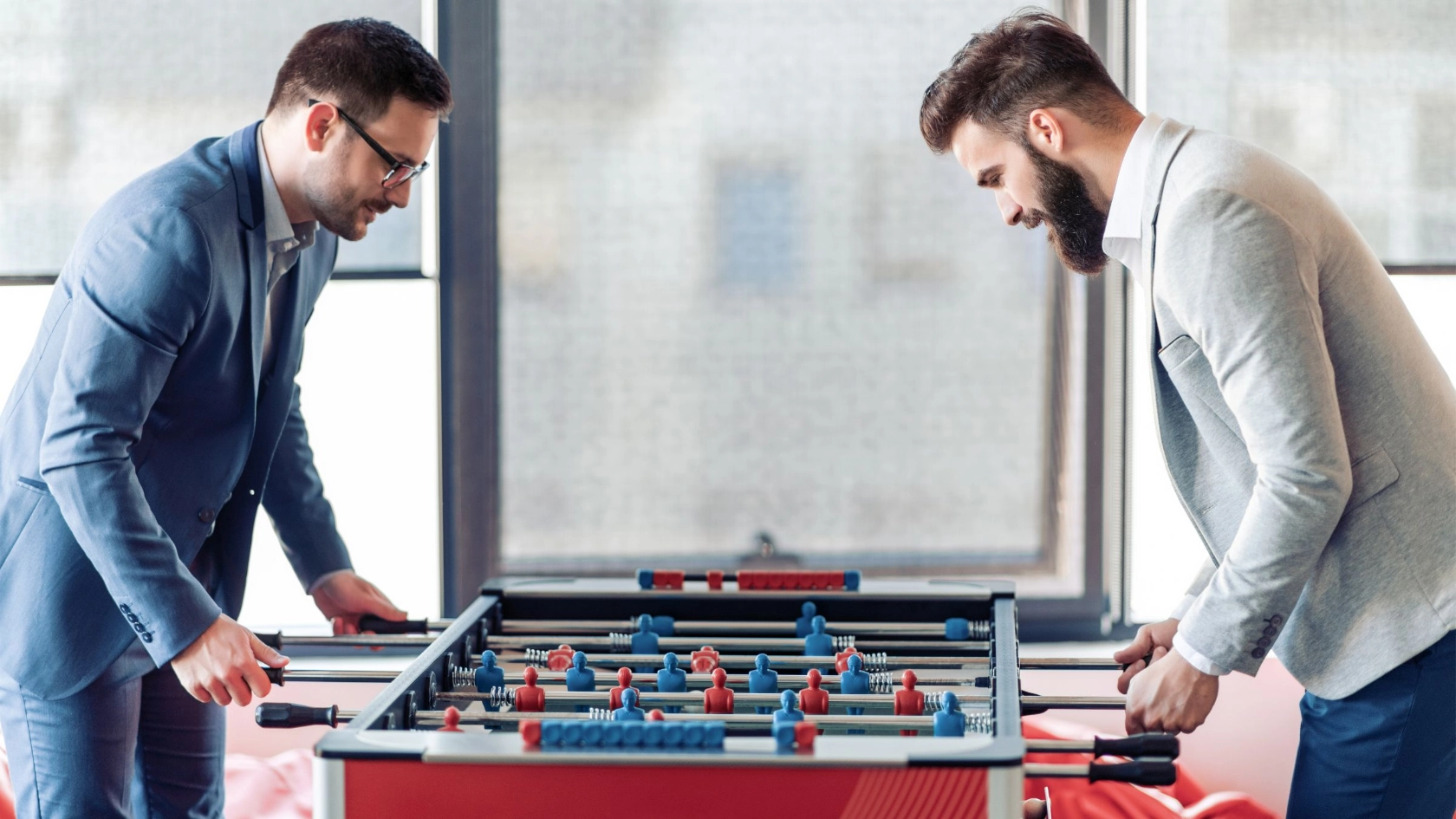 Zwei Kollegen spielen im Büro an einem Tischkicker
