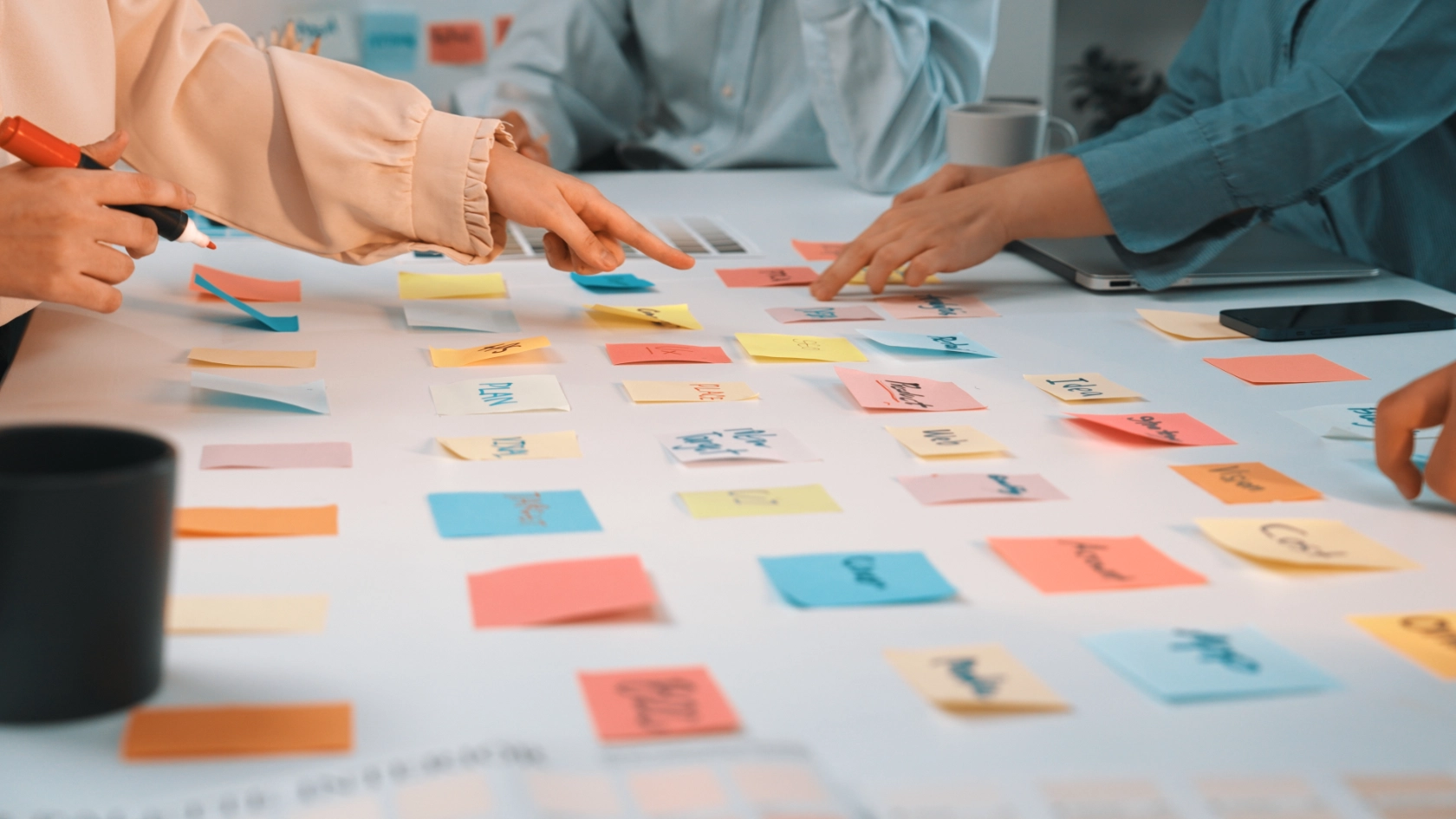 Ein Team arbeitet mit bunten Post-Its auf einem weißen Tisch.