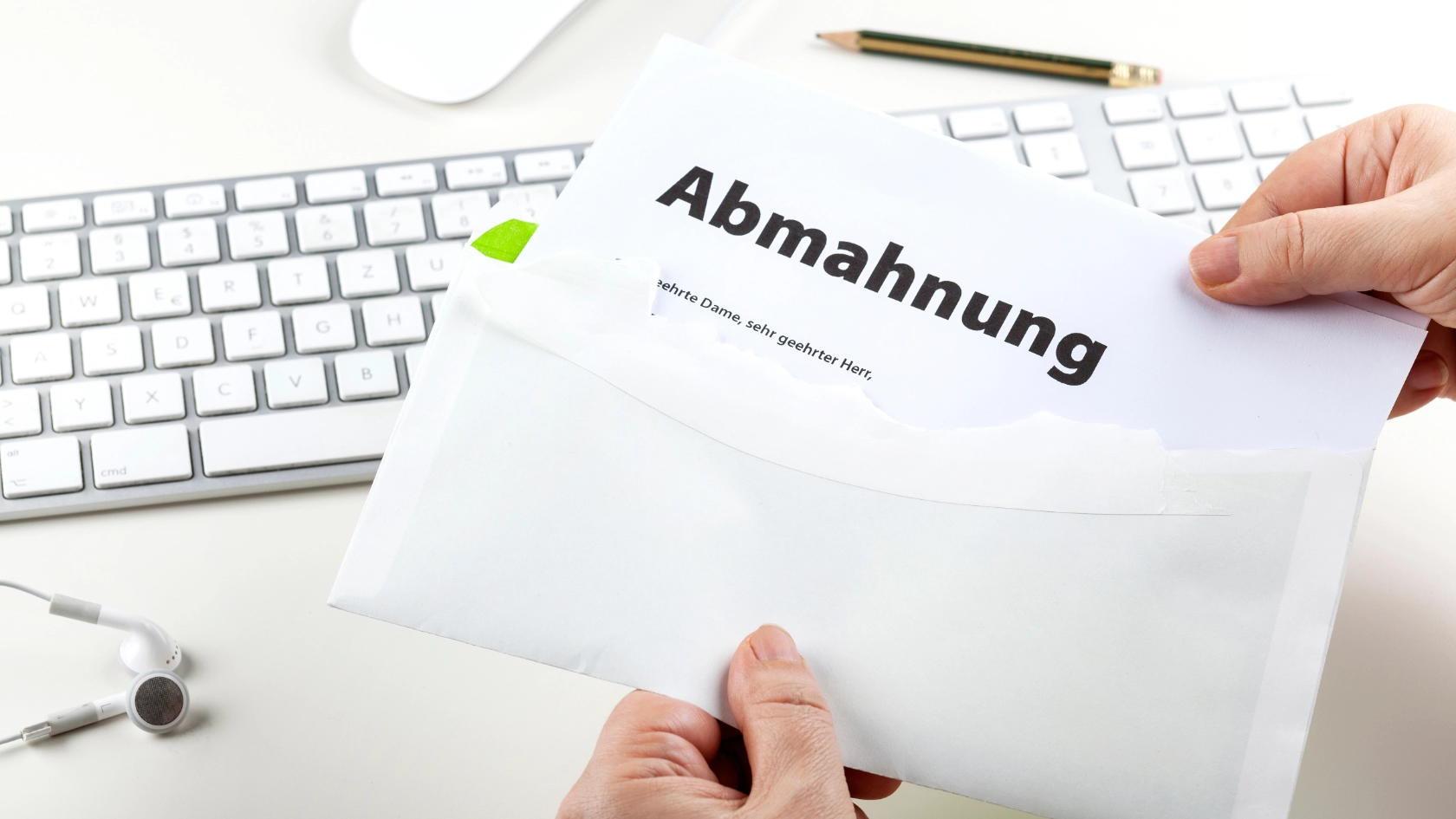 Brief mit Abmahnung wird geöffnet, Arbeitsplatz mit Tastatur im Hintergrund