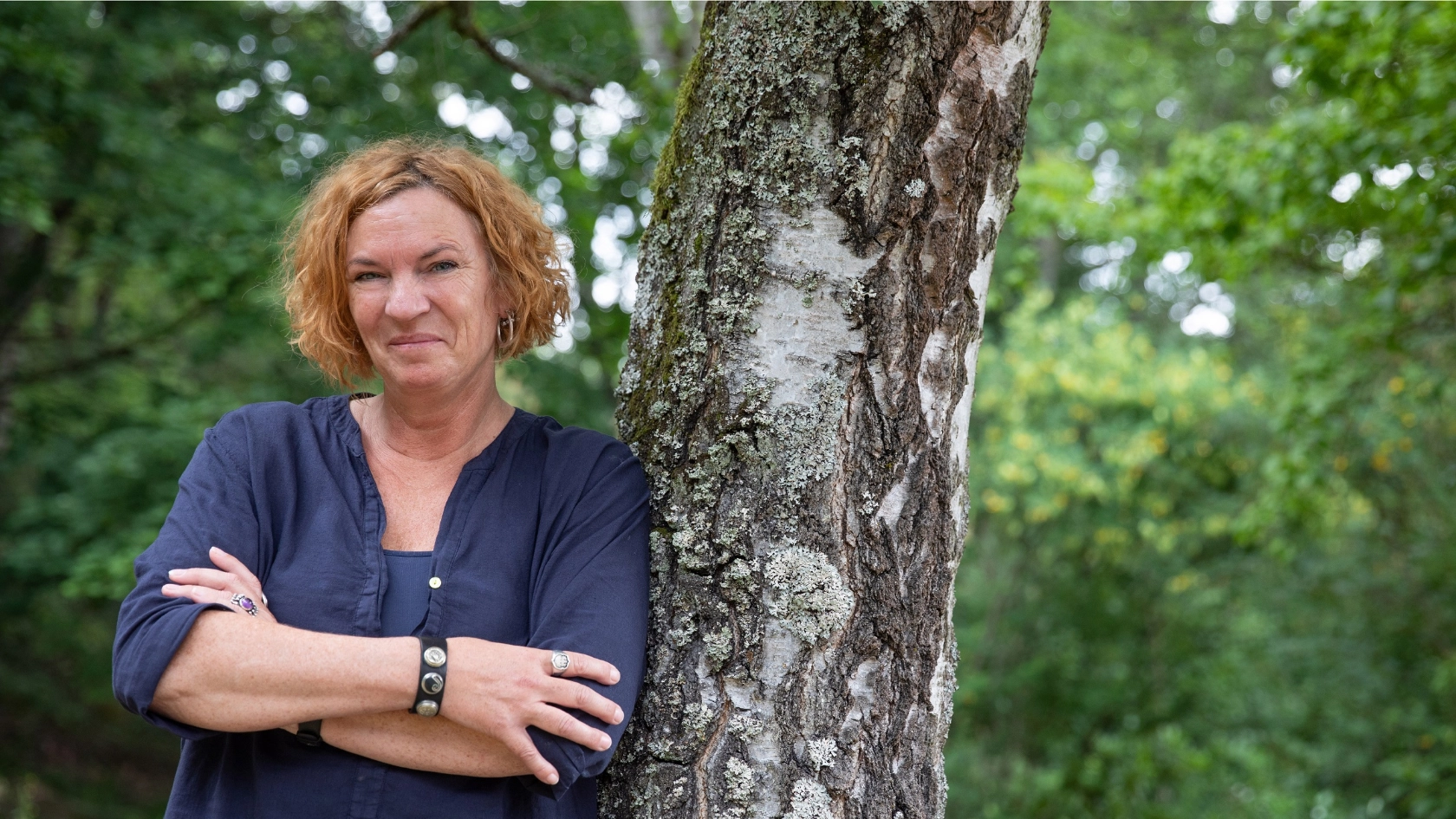 Resolute Frau lehnt am Baum