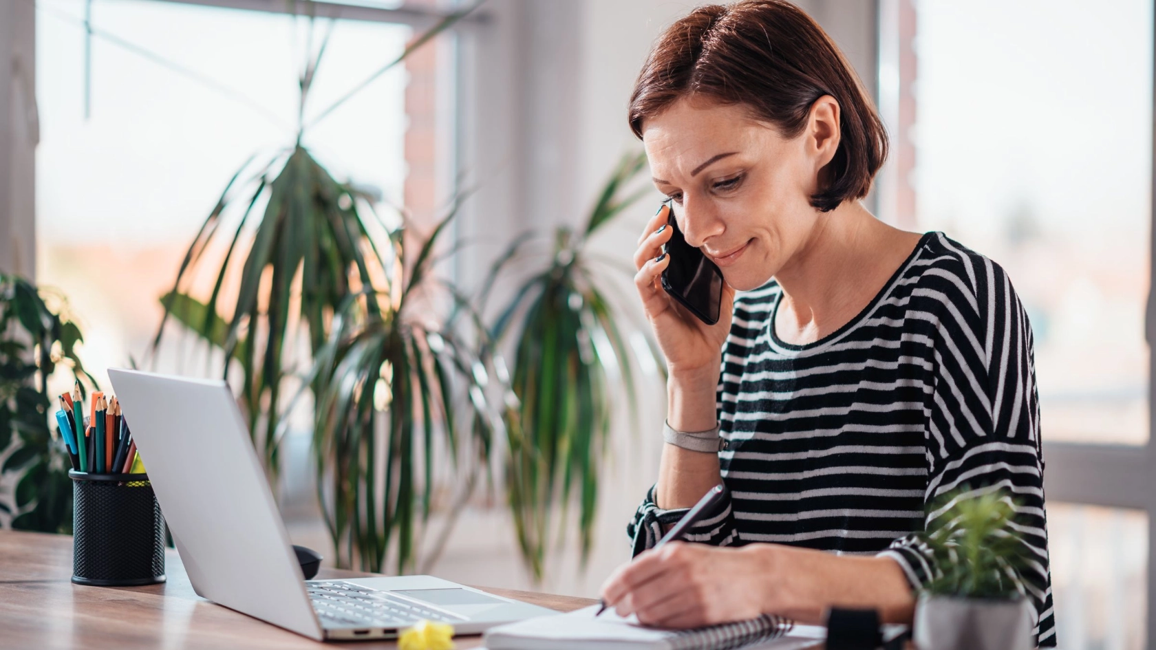 Frau sitzt im Homeoffice am Laptop und telefoniert