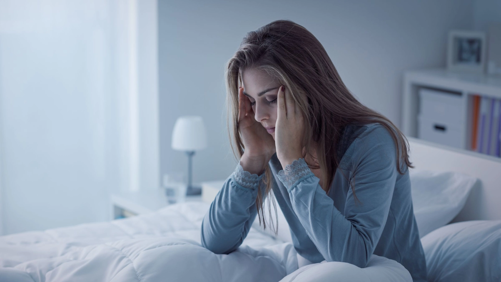 junge Frau sitzt müde in ihrem Bett