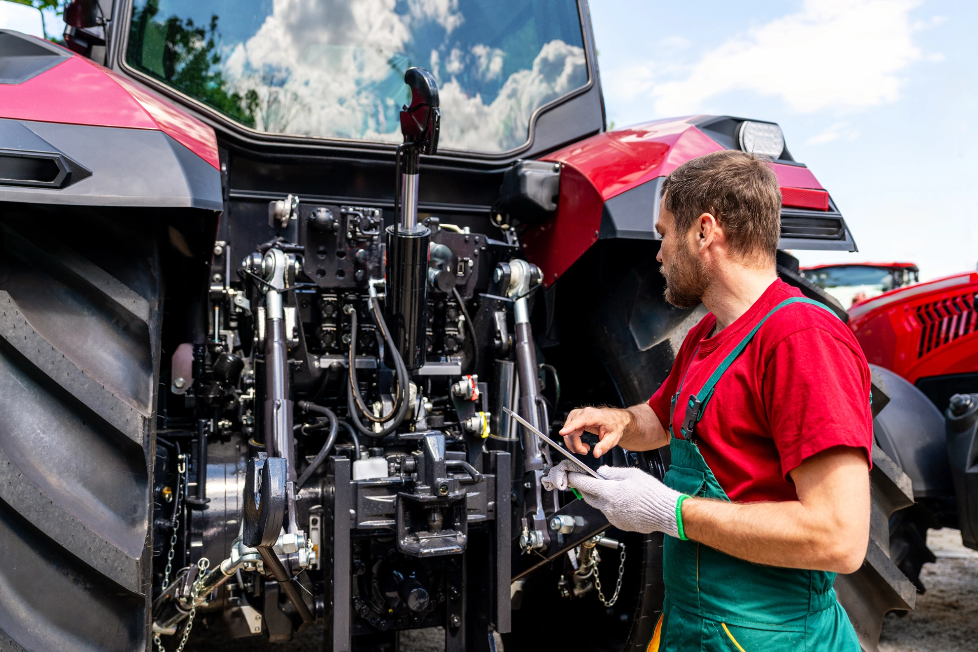 Ein männlicher Land- & Baumaschinenmechatroniker prüft einen Traktor mit einem Tablet