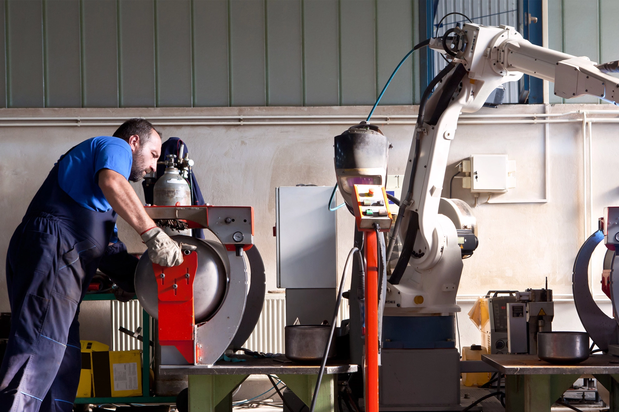 Ein Schweißroboter schweißt Kessel in einer Werkshalle 