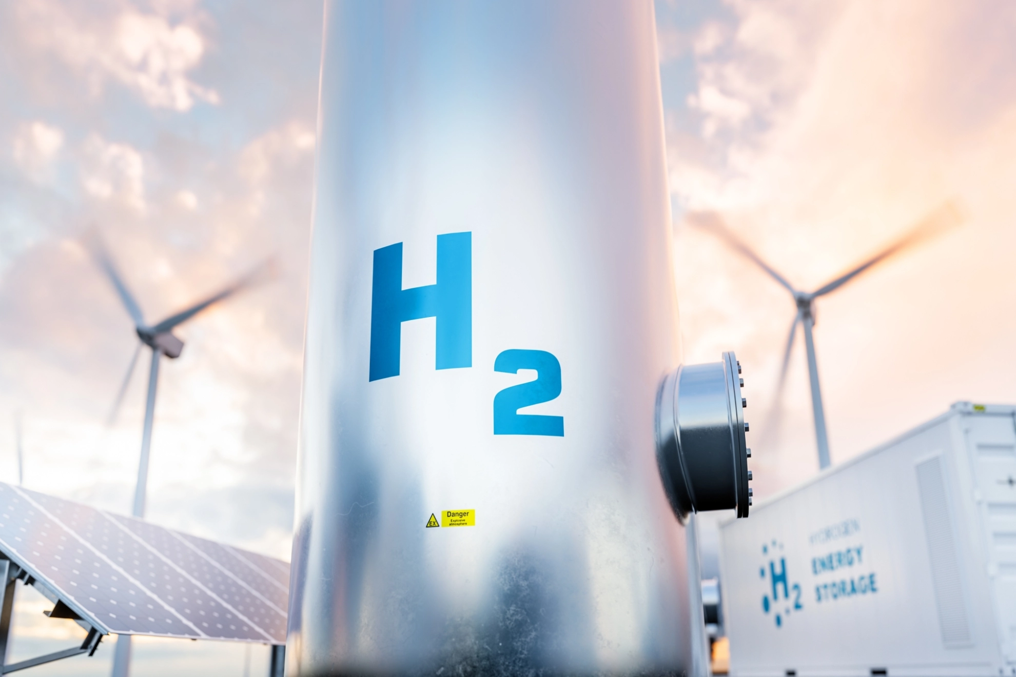 Wasserstoff-Energiespeicher mit Gastank, Sonnenkollektoren, Windkraftanlage und Energiespeicher-Container-Einheit im Hintergrund
