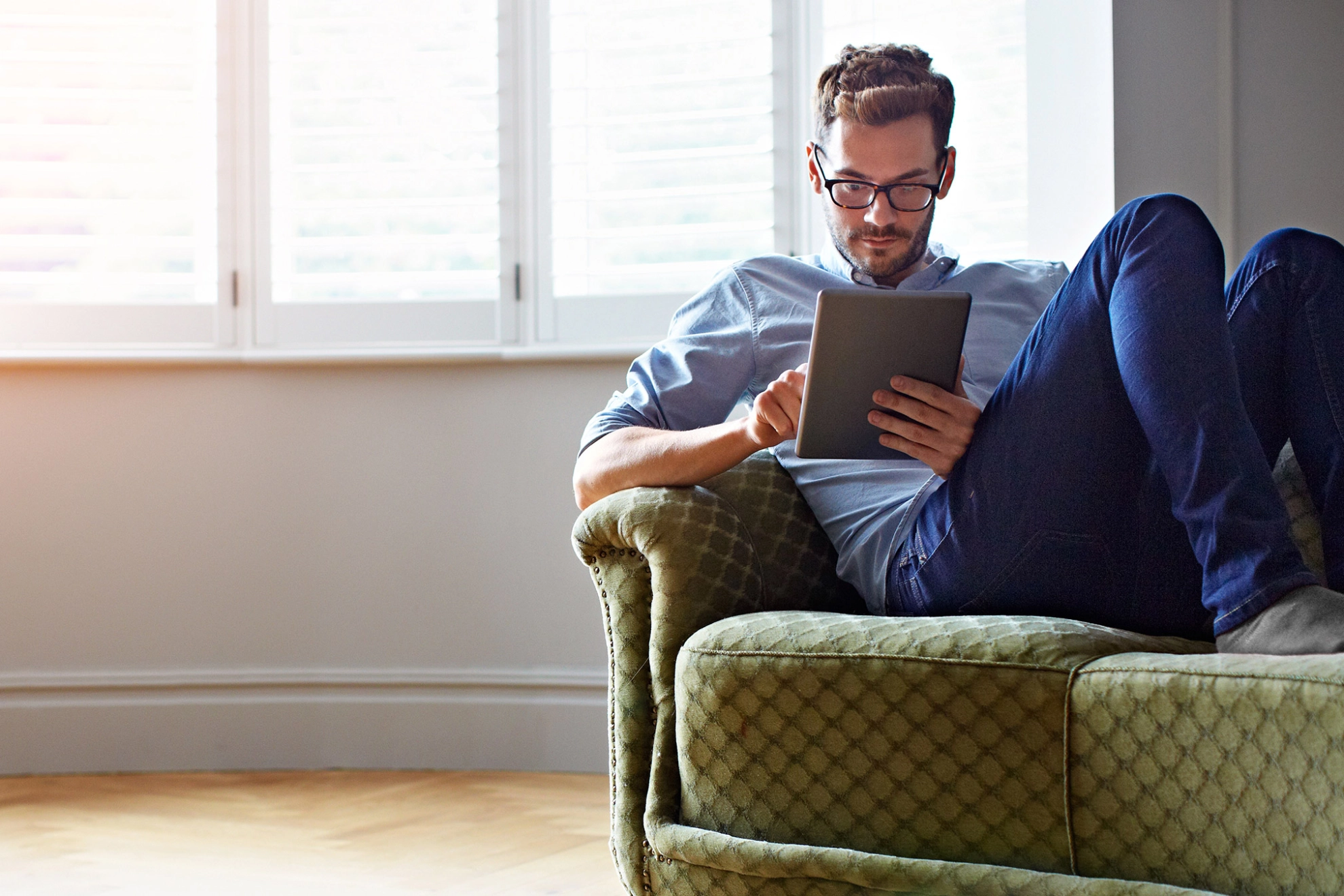 Mann mit Tablet auf dm Sofa