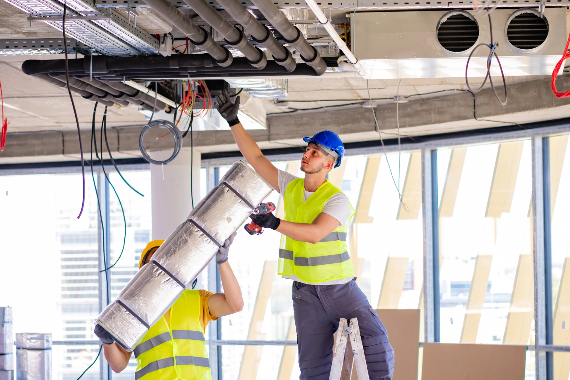 Beschäftigte richten eine Lüftungsanlage in einem Neubau ein