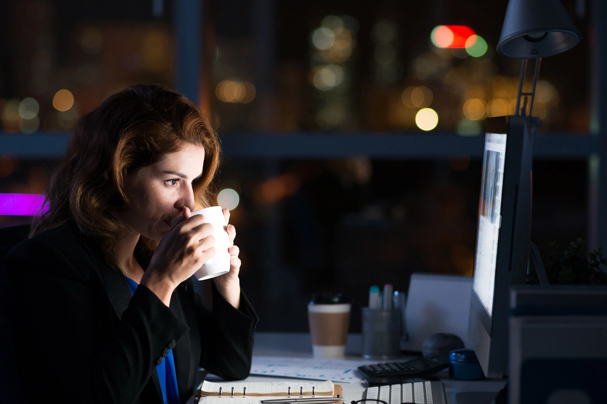 Eine Frau im Büro arbeitet Nachts am Computer