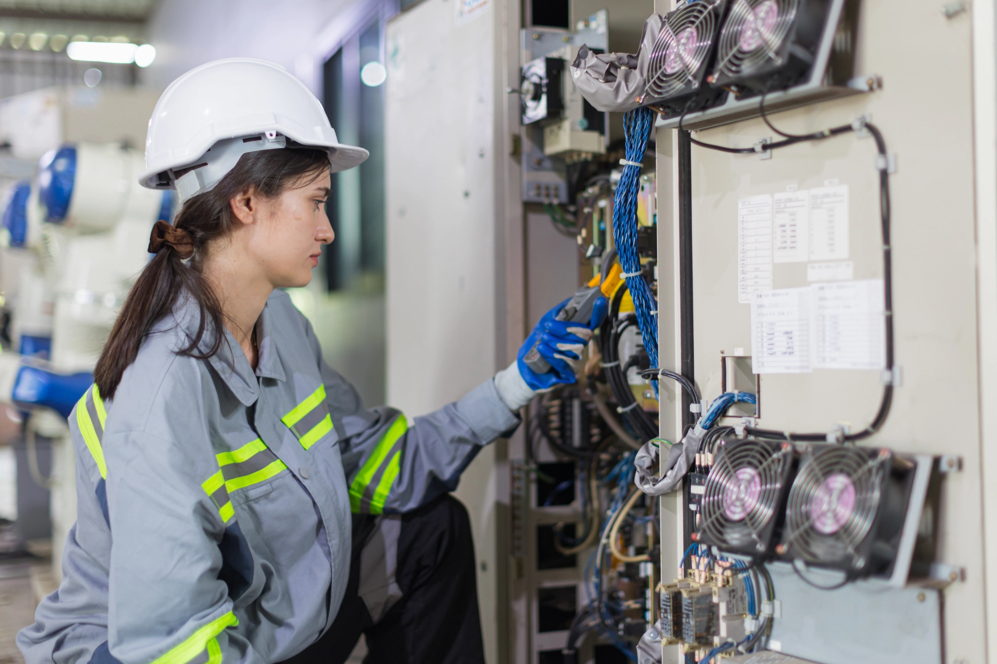 Elektronikerin prüft die Spannung an einem Schaltschrank.