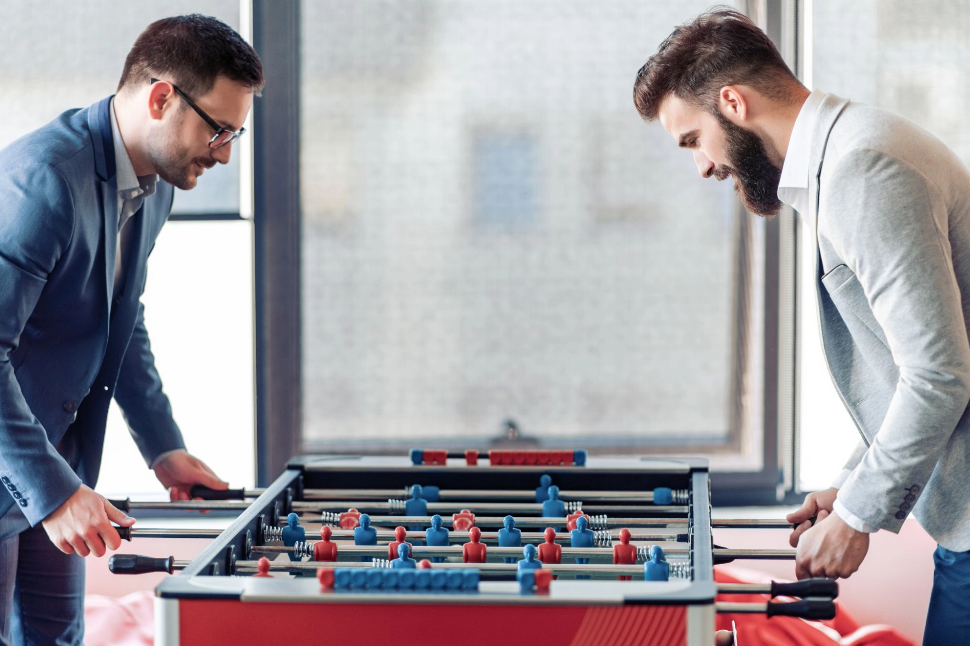 Zwei Kollegen spielen im Büro an einem Tischkicker