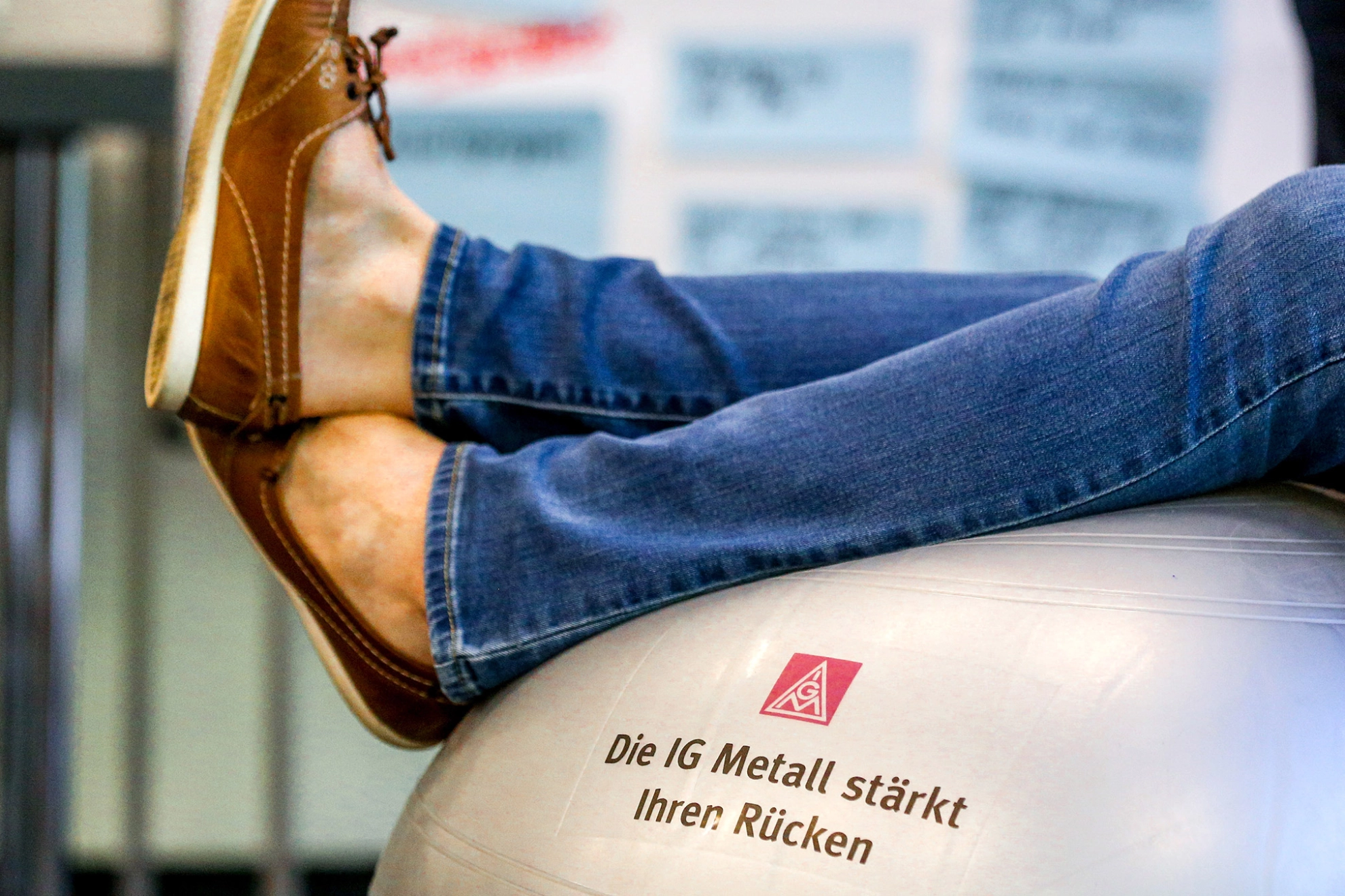 Beine, die auf einem silbernen Gymnastikball abgelegt sind.
