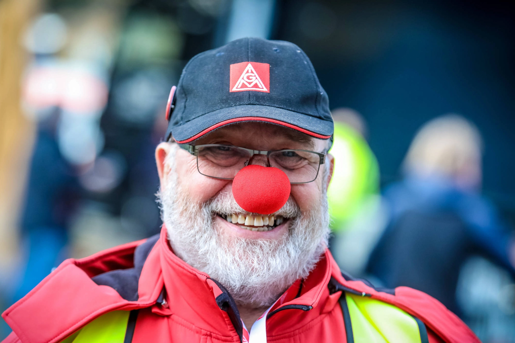 Ein lächelnder Mann mit roter Clownsnase und IG Metall-Kappe.