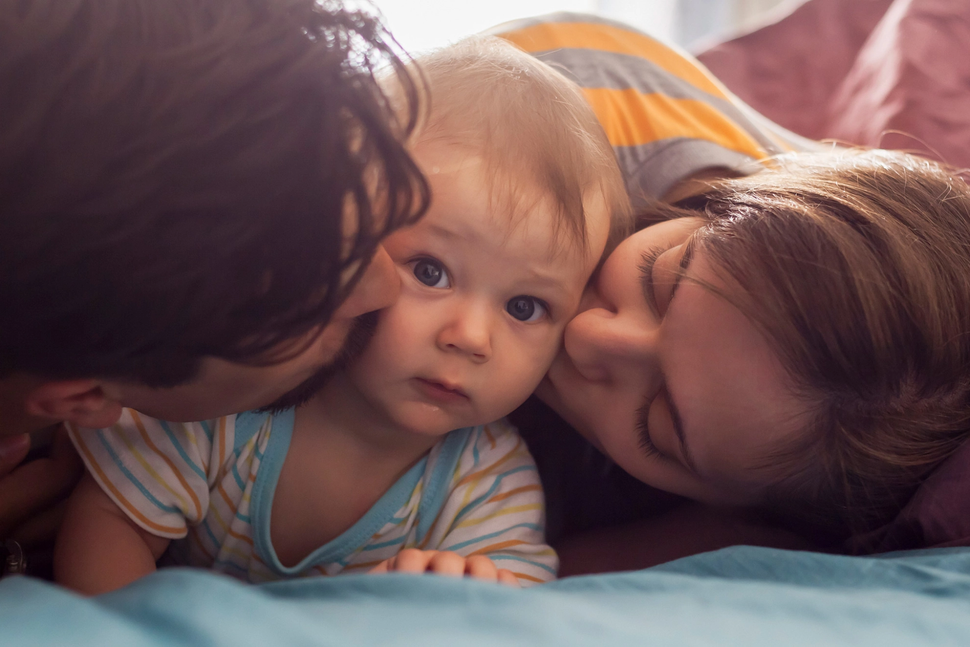 Eltern mit ihrem Kind liegen im Bett