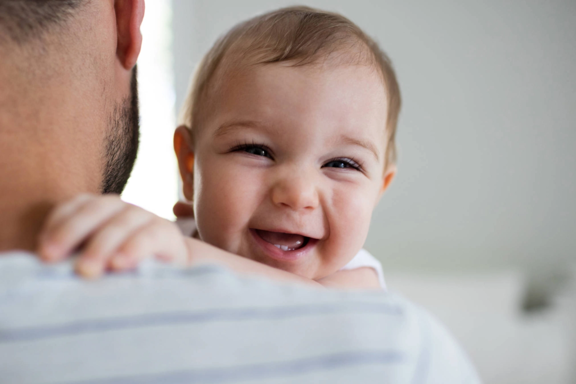 Ein lächelndes Baby auf dem Arm seines Vaters.