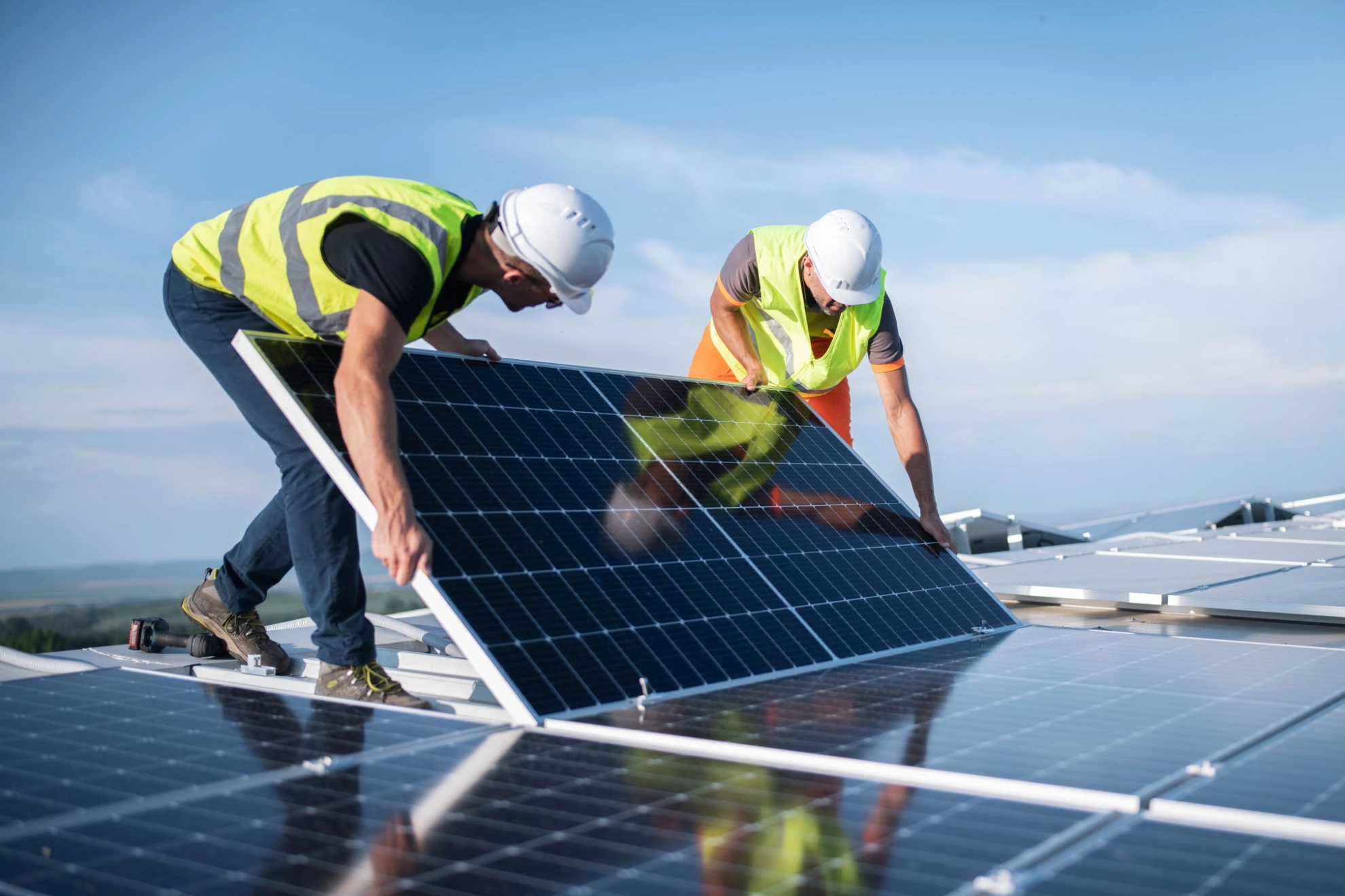 Zwei Techniker installieren eine Sonenkollektoren auf einem Dach