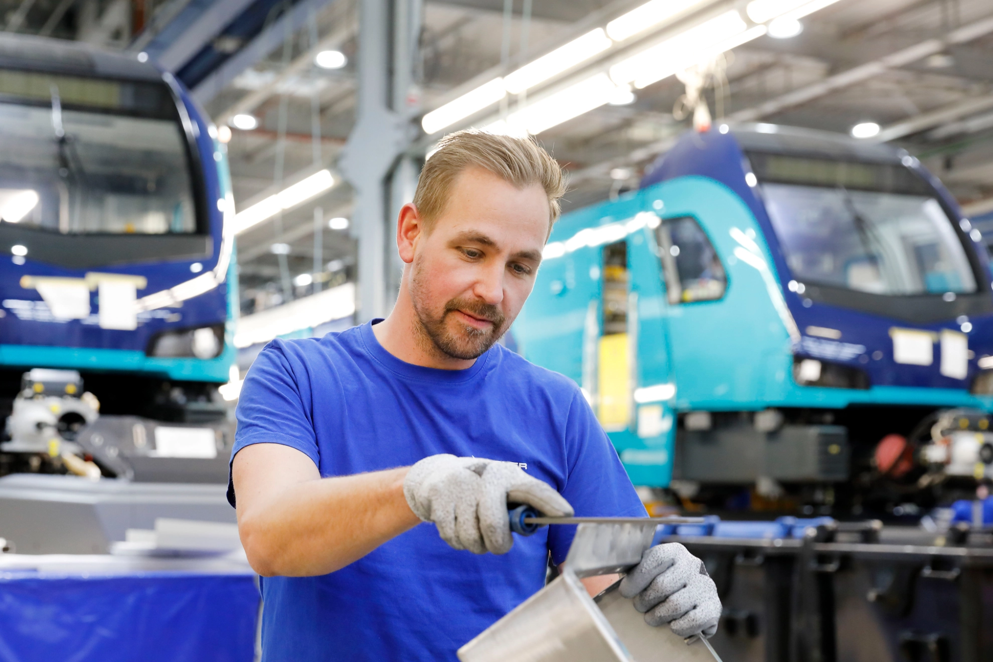 Ein Mitarbeiter feilt ein Metallteil beim Hersteller von Schienenfahrzeugen Stadler in Berlin