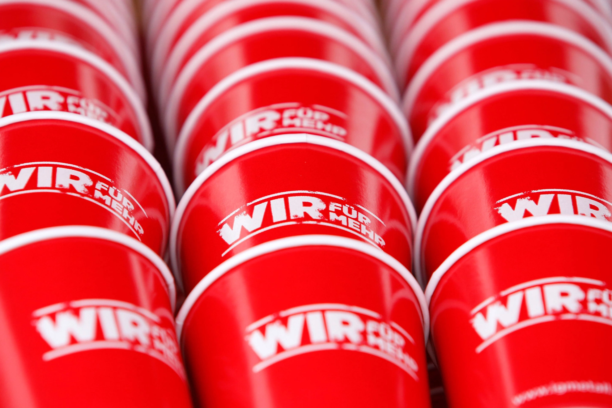 Rote Tassen mit 'WIR FÜR MEHR'-Druck.