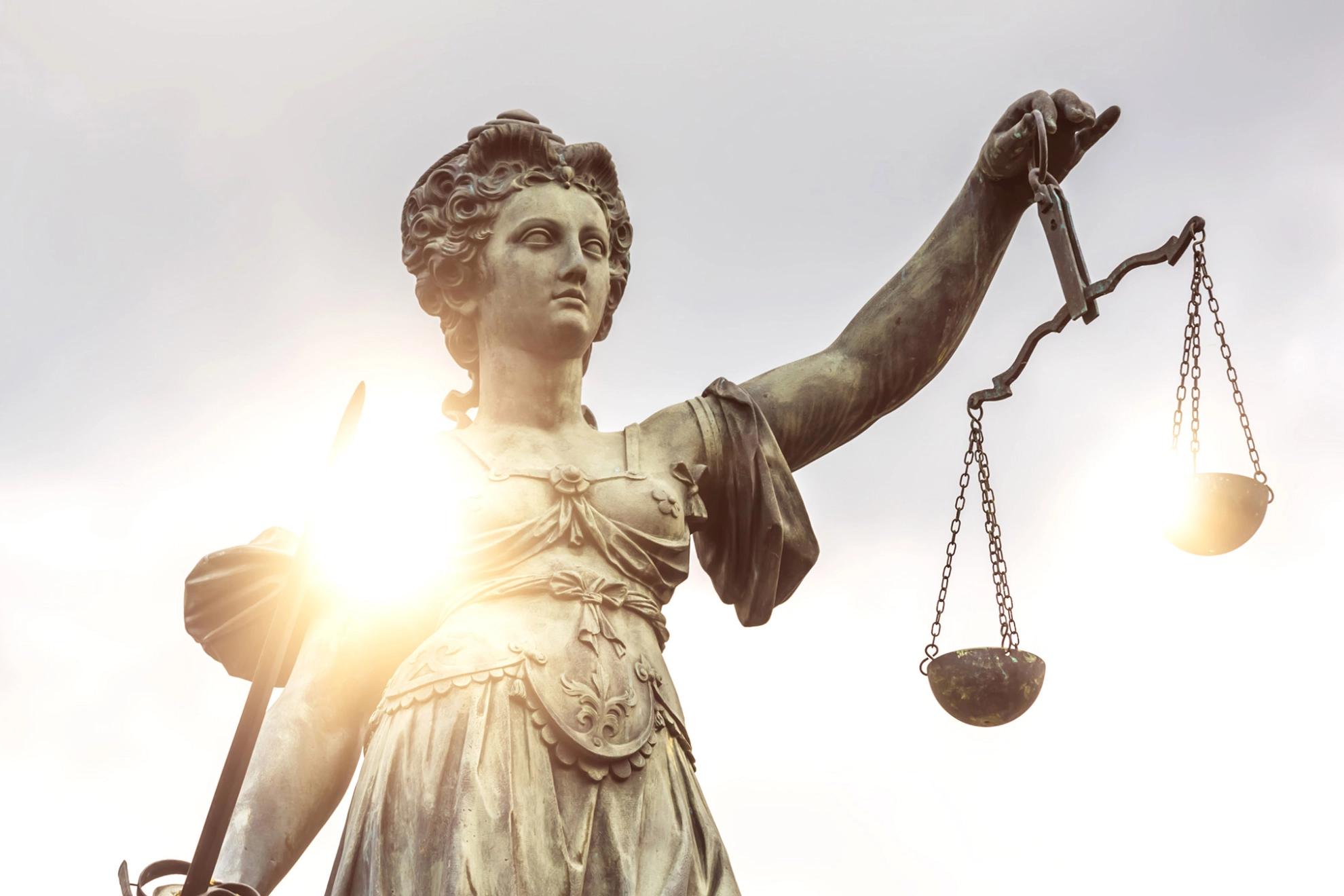 Eine Statue der Justitia wird von der Sonne angestrahlt.