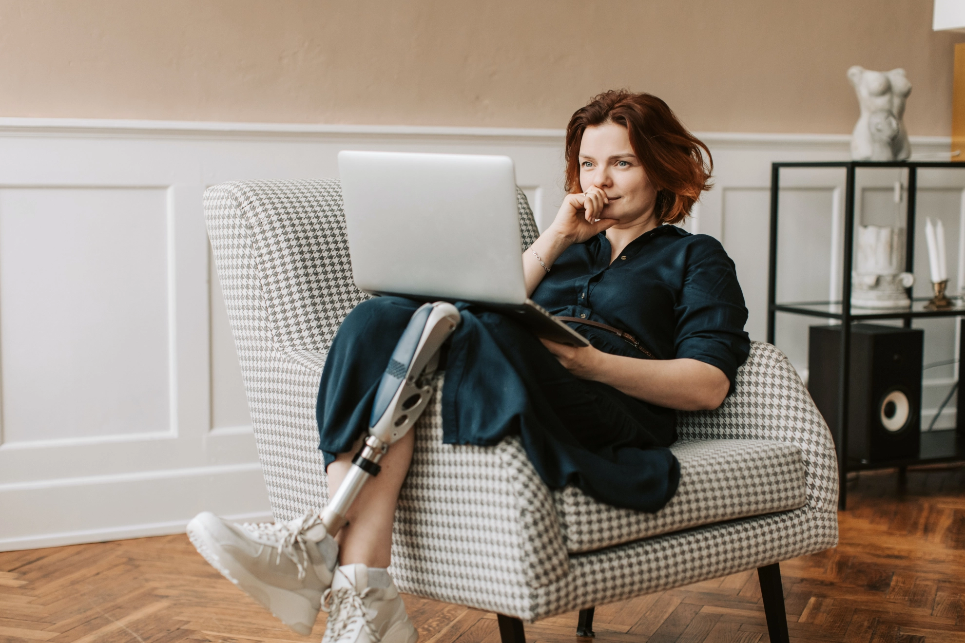 Frau mit Beinprothese lümmelt sich auf ein Sofa und liest in einem Laptop