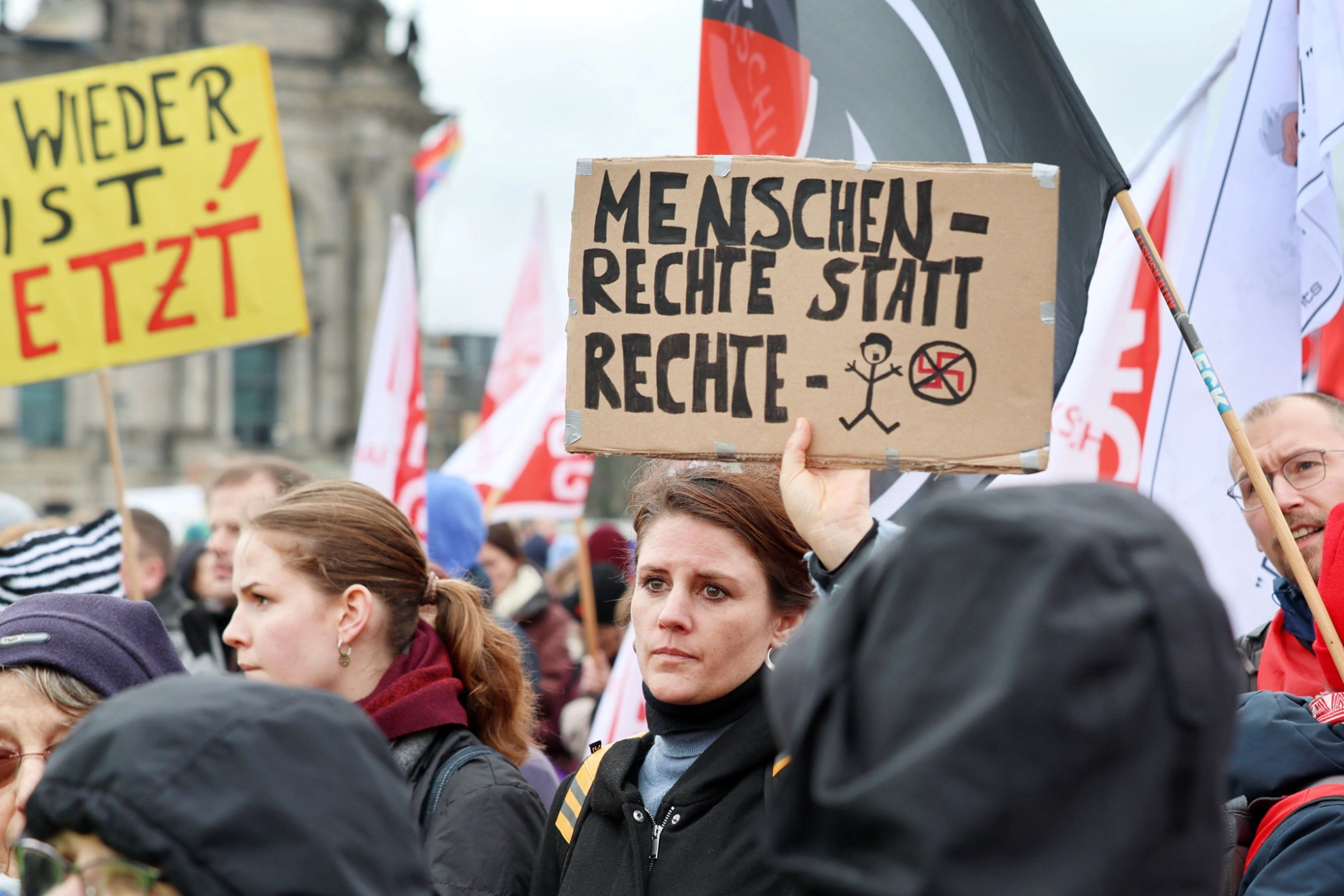 Menschenmenge bei einer Demo. Eine Frau hält ein Schild hoch mit der Aufschrift „Menschenrechte statt rechte Menschen“.