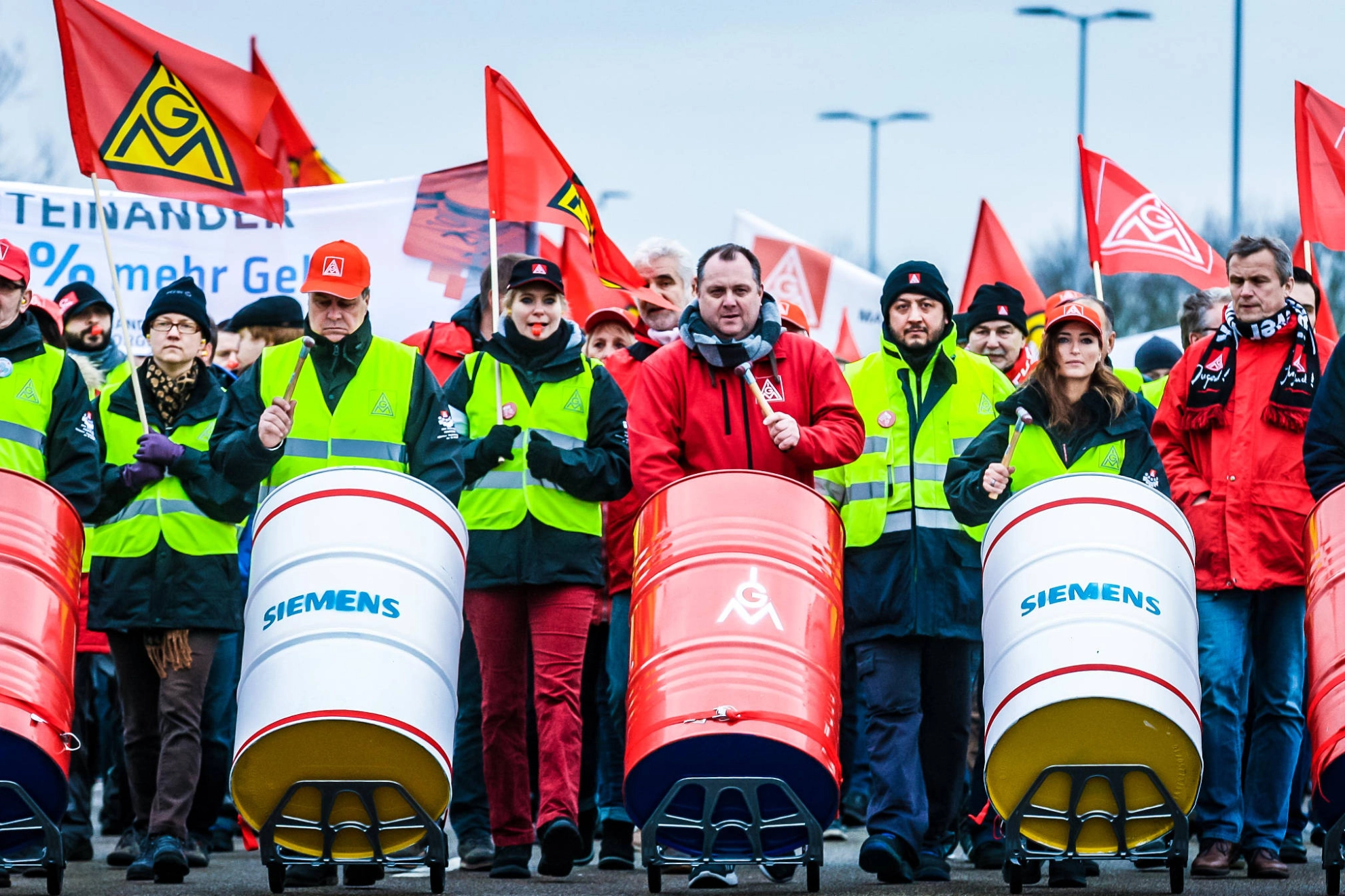 Streikende an der Spitze eines Demonstrationszuges, die auf Fässern trommeln.