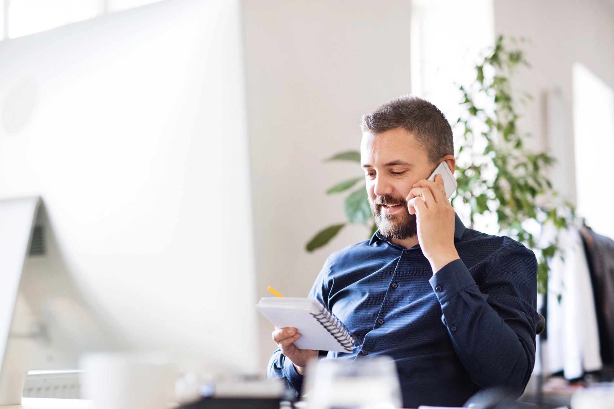 Mann telefoniert mit seinem Smartphone am Arbeitsplatz