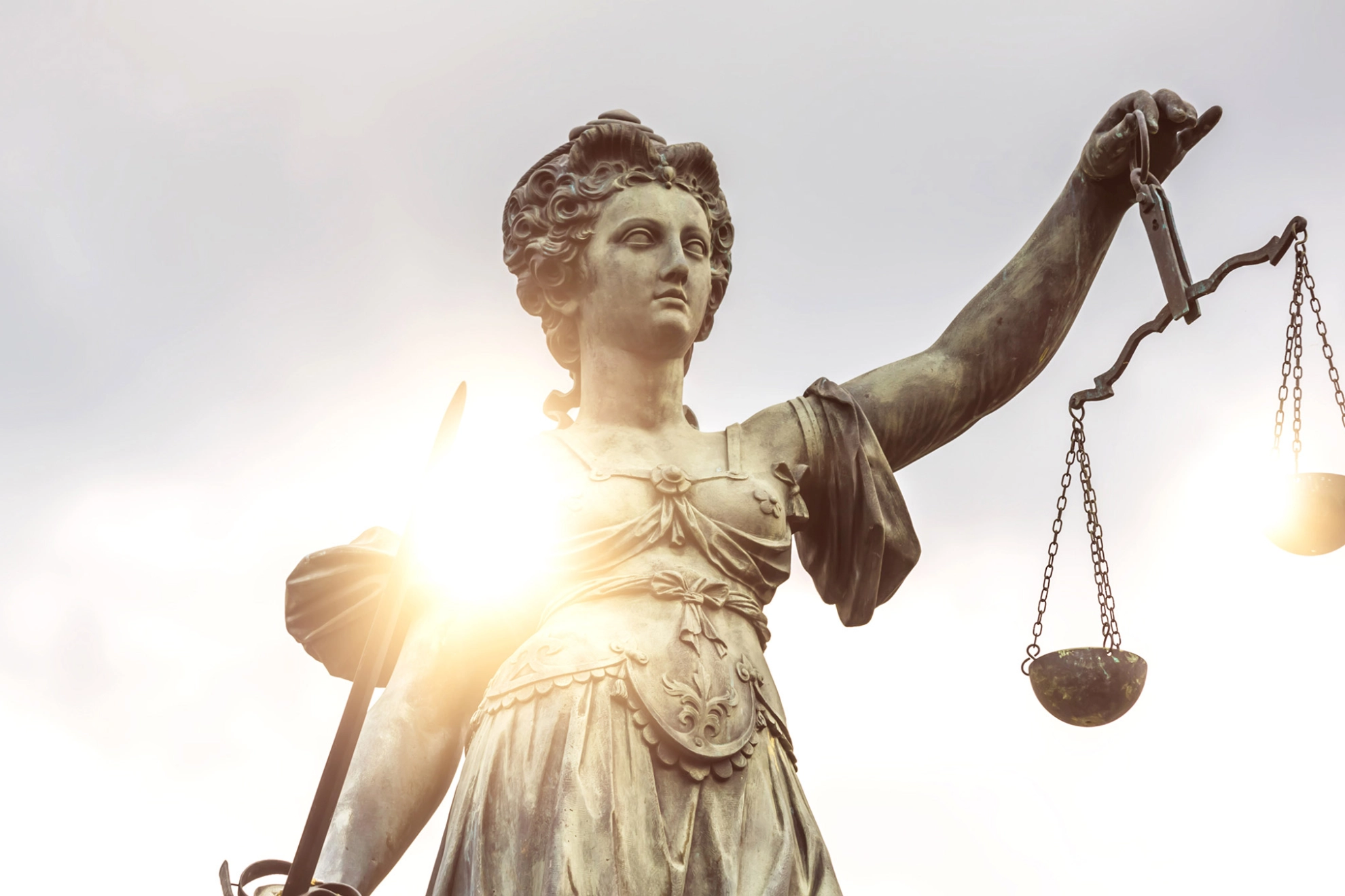 Eine Statue der Justitia wird von der Sonne angestrahlt.