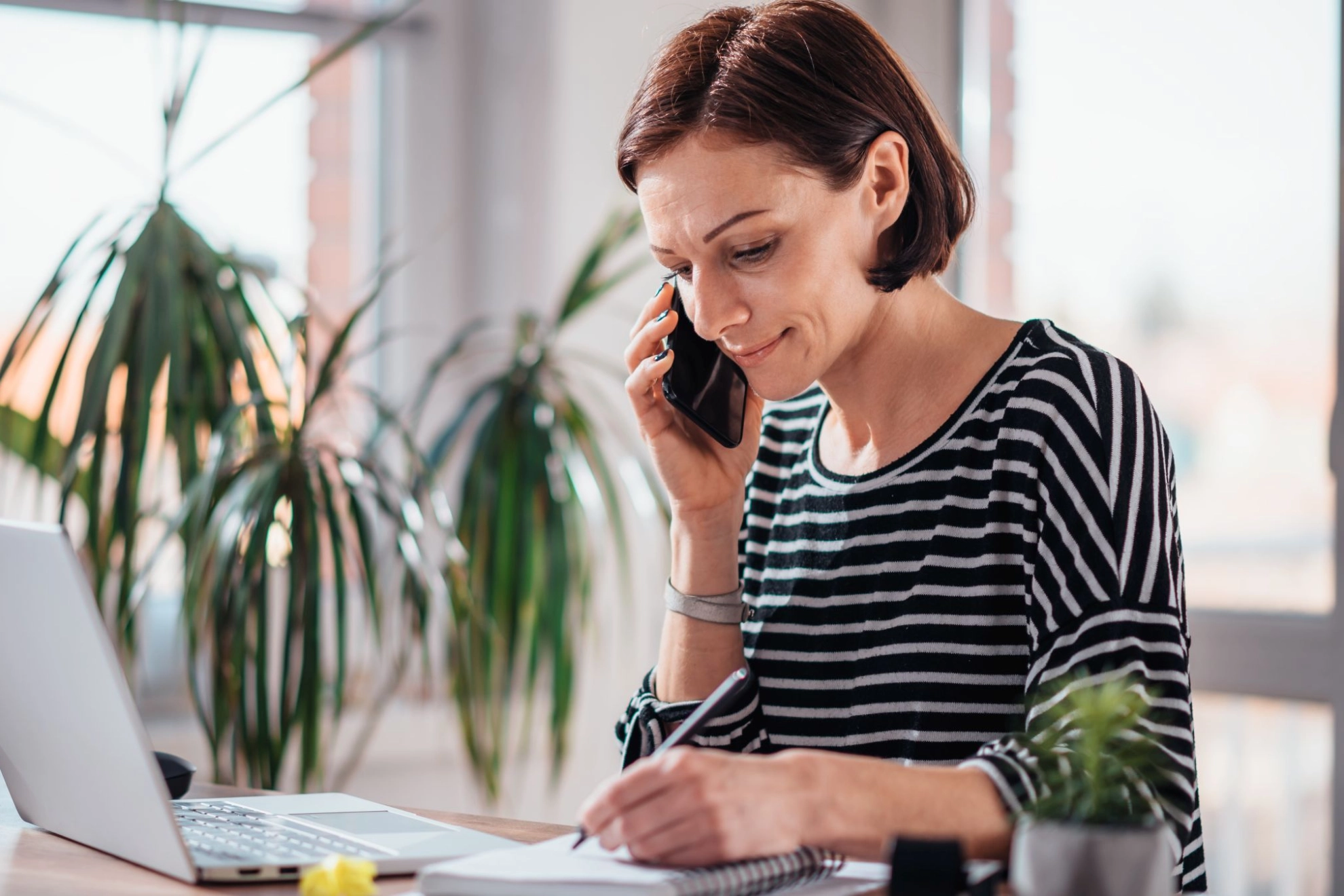 Frau sitzt im Homeoffice am Laptop und telefoniert