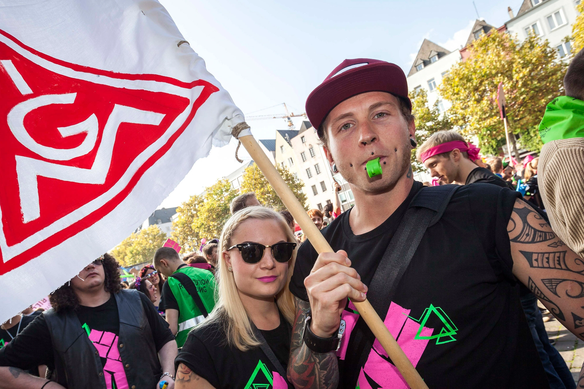 Junge Frau und junger Mann schwenken auf einer Demo die IG-Metall-Fahne.